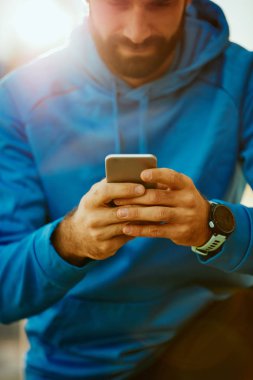 Akıllı telefon kullanarak spor Genç sakallı adamın kapatın. Sağlıklı yaşam konsepti.