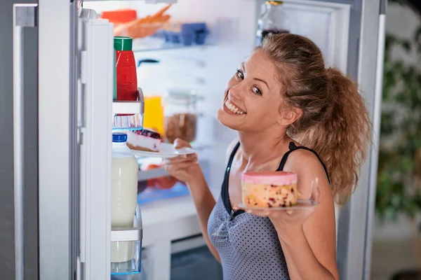 Frau Nimmt Kuchen Während Sie Vor Geöffnetem Kühlschrank Steht — Stockfoto