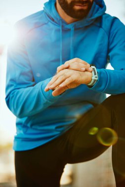 Sportif sakallı biri diz çökmüş ve kronometre ayarını kapatın. Sağlıklı yaşam konsepti.