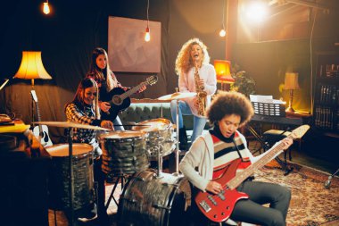 Caz müzik kızlar. Diğer iki saksafon ve davul çalmaya arka plan, ön plan bir kadın bas gitar çalıyor ve içinde. Ev stüdyosu iç.