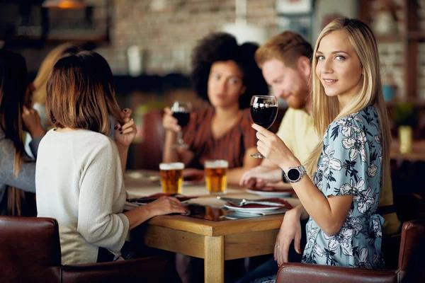 Žena Při Pohledu Fotoaparát Drží Sklenku Vína Při Posezení Restauraci — Stock fotografie