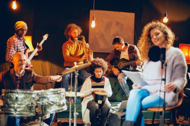 Caz Orkestrası Konser için hazırlanıyor. Ön plan kadının grubun geri kalanı şarkı bas gitar, clavier ve akustik gitar oynamak. Ev müzik stüdyosu iç.