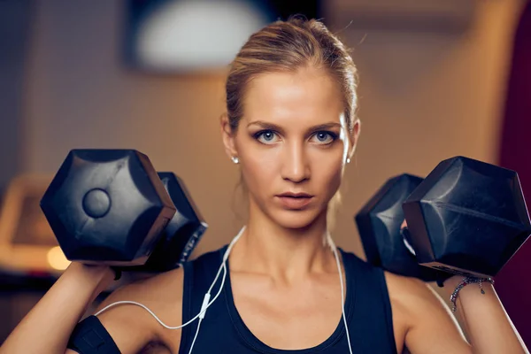 Close up of woman lifting dumbbells. Looking in camera. Healthy