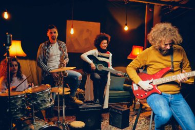 Bas gitarist sandalyede otururken gitar çalmak. İçinde TZB