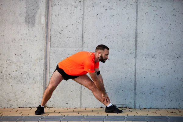 Sportif adam çalıştırmadan önce bacaklarını germe. Sağlıklı yaşam konsepti.