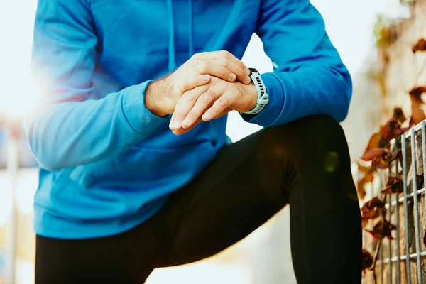 Primer plano del hombre barbudo deportivo arrodillado y el cronómetro de ajuste. concepto de estilo de vida saludable . — Foto de Stock