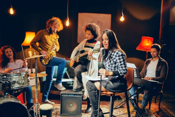 Band practice in home studio. Woman singing while rest of the band playing instruments. — Stock Photo, Image