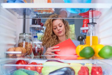 Kadın alarak donuts dolap dolusu yiyecek gelen kutusu. Resim buzdolabının içinden çekilen.