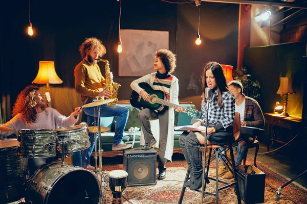 Zenekar gyakorlat házi stúdiójában. Nő énekel, miközben a banda játszik eszközök. — Stock Fotó