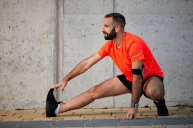 Sportif adam çalıştırmadan önce bacaklarını germe. Sağlıklı yaşam konsepti.