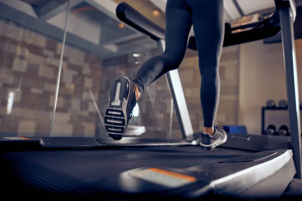 Primer plano de las piernas de la mujer corriendo en la cinta de correr. Interior del gimnasio . —  Fotos de Stock