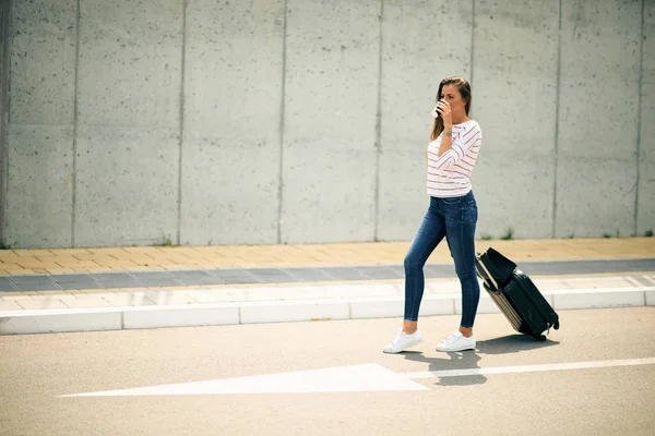 Mujer sosteniendo café y equipaje mientras camina por la calle . — Foto de Stock