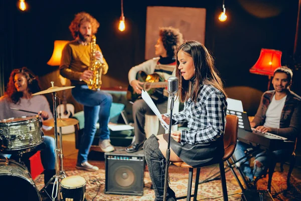 De praktijk van de band in thuisstudio. Vrouw zingt terwijl de rest van de band spelen van instrumenten. — Stockfoto