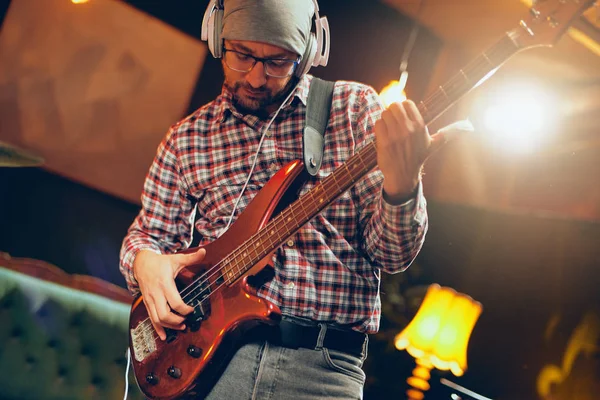 Focused Caucasian musician playing bass guitar with earphones on ears. Full length. — Stock Photo, Image