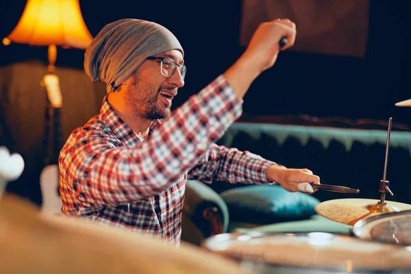 Caucasian drummer playing his instrument while sitting in home studio. — Stock Photo, Image