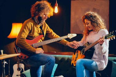 Akustik gitar bas çalmaya adam beyaz kadın. Ev stüdyosu iç.