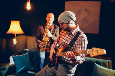 Bas gitar ve saksafon ev stüdyosunda oynayan iki beyaz büyük müzisyenler.