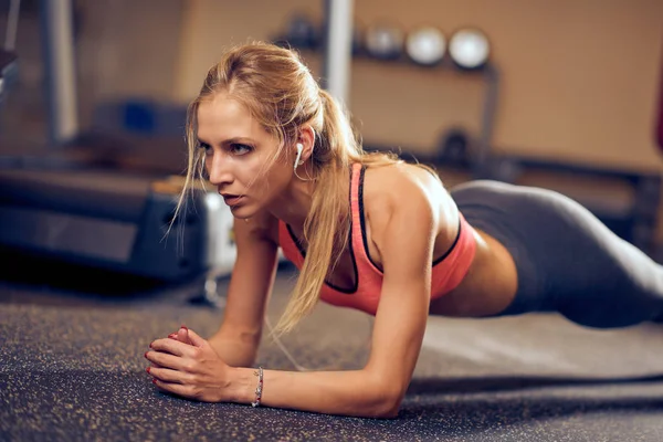 Kobieta robi deski na podłodze sali gimnastycznej. Koncepcja zdrowego stylu życia. — Zdjęcie stockowe