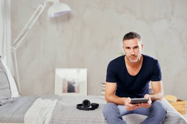 Beyaz adam yatakta yatak odasında oturma ve tablet kullanarak kırklı.