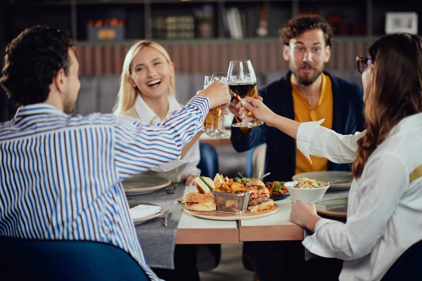 Quatro freinds muliétnicos felizes vestiram torcida casual inteligente com álcool enquanto sentado no restaurante . — Fotografia de Stock