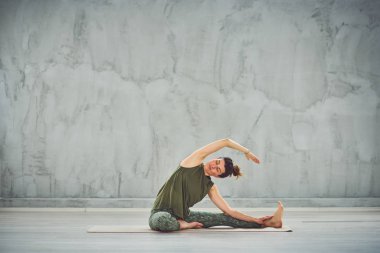 Mat otururken çekici esmer germe bacak.