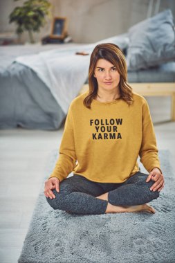 Güzel Kafkas esmer Lotus yoga duruş yatak odasında halı üzerinde oturan.