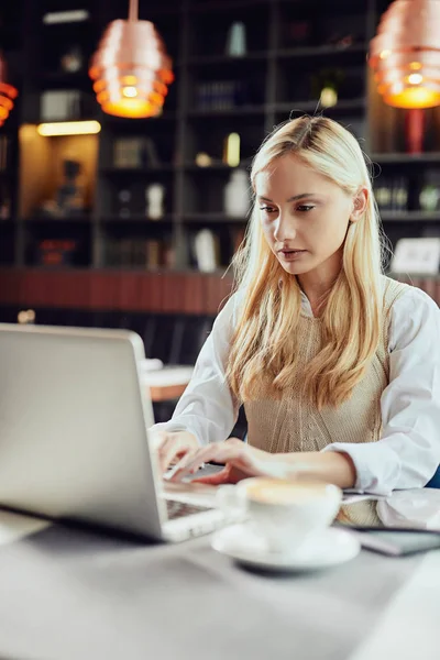 Kafe 'de oturup dizüstü bilgisayar kullanarak şık giyinen, ciddi, beyaz, sarışın bir iş kadını.. — Stok fotoğraf