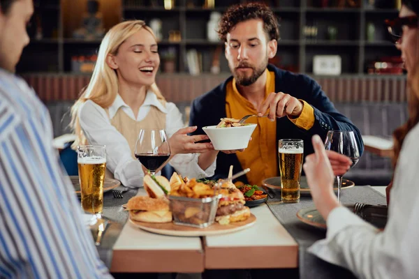 Többnemzetiségű barátok ül étterem, alkoholfogyasztás, csevegés és miután hamburgerek vacsorára. — Stock Fotó