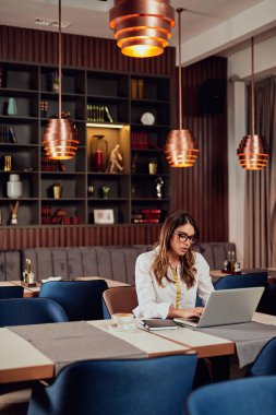 Çekici Kafkas iş kadını kafede oturan akıllı rahat giyinmiş ve büyük proje bitirmek için dizüstü bilgisayar kullanarak.