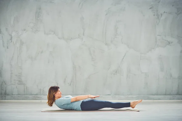 Side biew av unga kaukasiska brunett liggande och gör yoga på mattan. — Stockfoto