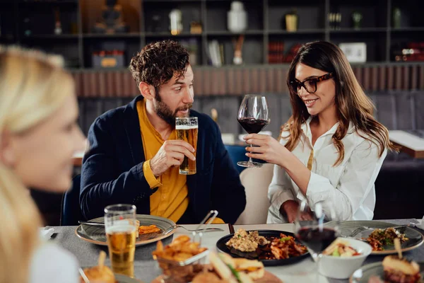 Vrienden gekleed Smart Casual juichen met alcohol terwijl zittend in restaurant. — Stockfoto