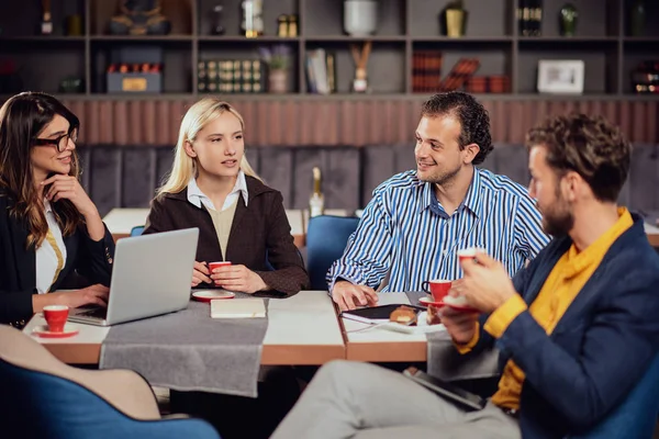 Four multiethinc successful colleagues sitting in cafeteria on lunch pause, drinking coffee and discussing about new project. — Stock Photo, Image