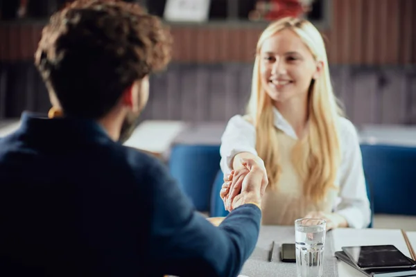 Two business partners shaking hands while sitting in coffee shop — Stock Photo, Image