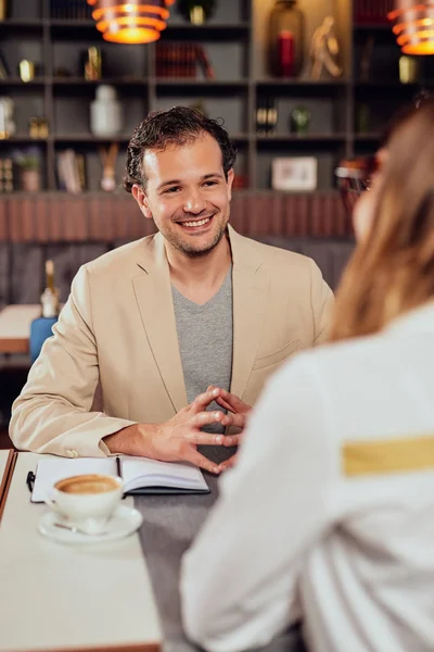 Twee multiculturele lachende collega's gekleed Smart Casual zitten in restaurant en discussiëren over project. — Stockfoto