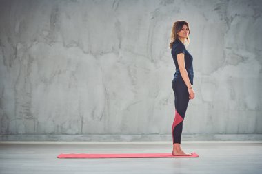 Güzel gülümseyen Kafkas esmer mat yalınayak ayakta ve yoga egzersizleri yapmaya hazırlanıyor.