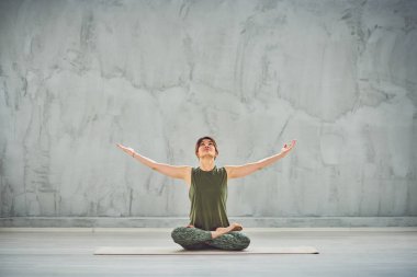 Nilüfer duruşu içinde paspas Üzerinde oturan beutiful kadın.