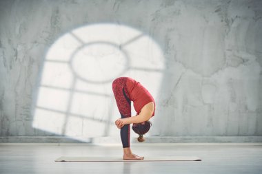 Kırmızı spor güzel Kafkas esmer yan görünümü Gorilla yoga poz paspas üzerinde yalınayak ayakta giymek.