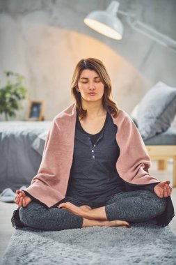 Güzel Kafkas esmer Lotus yoga duruş yatak odasında halı üzerinde oturan.