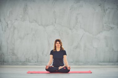 Nilüfer duruşu içinde paspas Üzerinde oturan beutiful kadın.