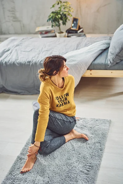 Attractive Caucasian brunette sitting on rug in bedroom in Maric — Stock Photo, Image