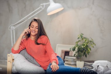 Rahat yatak odasında yatakta yalan ve Evet sevimli gülümseyen beyaz esmer giyinmiş.