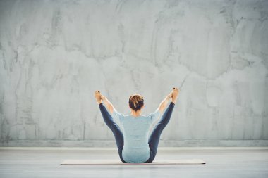 Mavi spor giyim güzel Kafkas esmer sırtları ile tekne yoga pozisyonda paspas üzerinde oturan döndü.