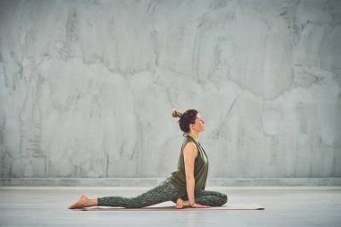 Muhteşem uyum Kafkas esmer yarım güvercin yoga mat yalınayak poz yapıyor.