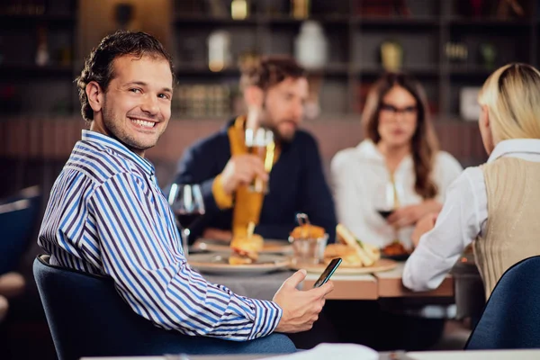 Hombre árabe joven vestido elegante informal sentado en la cena en el restaurante y el uso de teléfono inteligente . — Foto de Stock