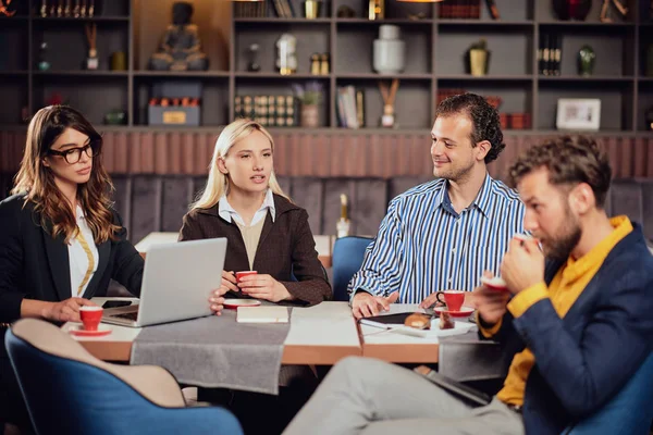 Four multiethinc successful colleagues sitting in cafeteria on lunch pause, drinking coffee and discussing about new project. — Stock Photo, Image