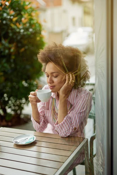 Mulher de raça mista atraente sentado no café e desfrutando de seu café . — Fotografia de Stock