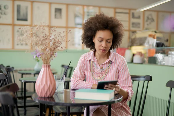 Aantrekkelijke mixed race vrouw in gestreepte roze jurk zitten in Cafe en het gebruik van Tablet. — Stockfoto