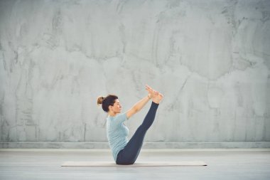 Tekne yoga pozisyonda paspas üzerinde oturan mavi spor giyim güzel Kafkas esmer.