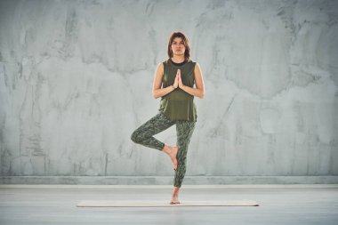 Yarım lotus poz mat üzerinde duran Büyüleyici esmer.