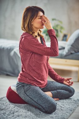 Sevimli Kafkas esmer yatak odasında yatakta oturan ve yoga egzersizleri yapıyor.